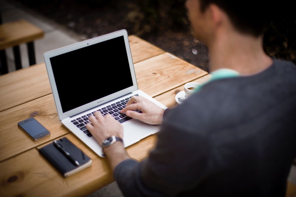 Publisher typing on a laptop at a wooden desk while planning affiliate website content