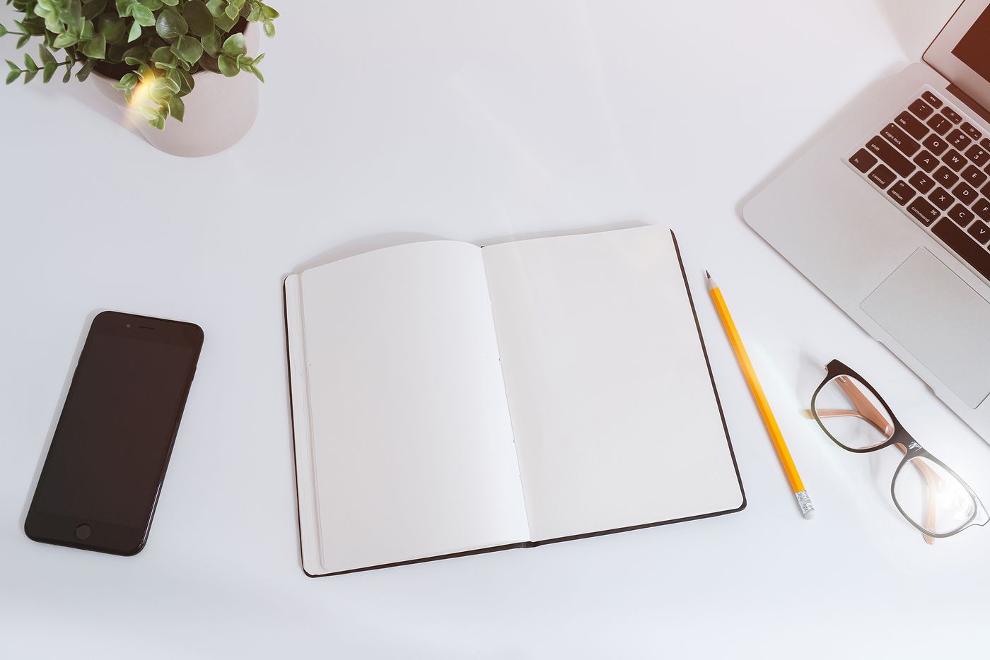 Notebook, smartphone and laptop on a white desk used to plan affiliate commissions